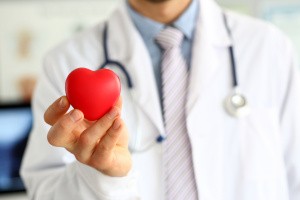 medico con camice e stetoscopio che mostra un cuore stilizzato